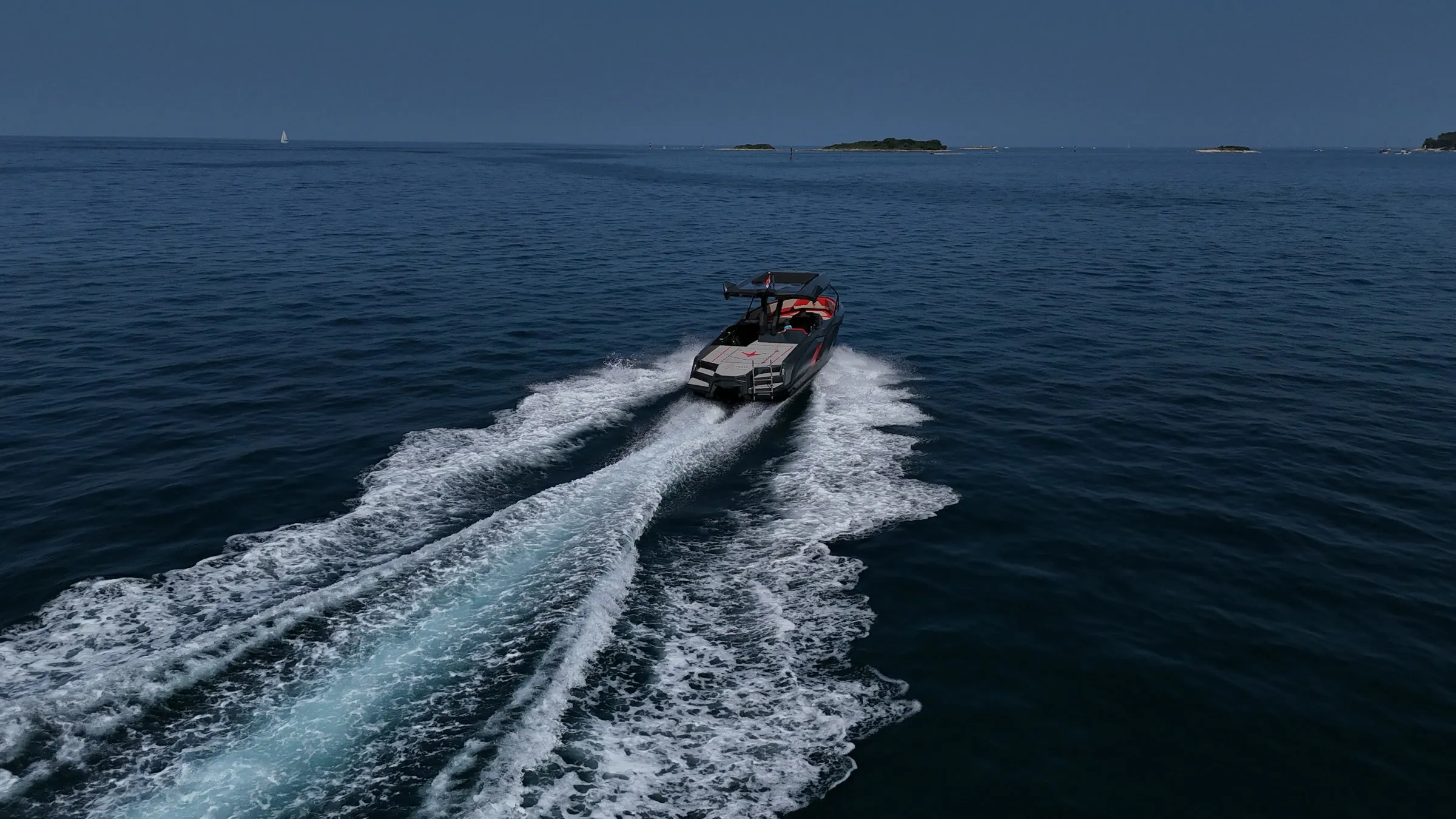 Brod plovi otvorenim morem, za njim duga brazda, na horizontu otoci